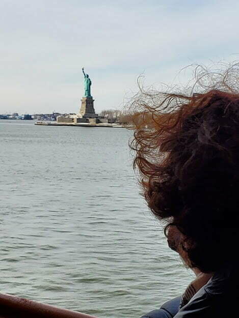 Susan overlooking the water where in the distance stands the Statue of Liberty.