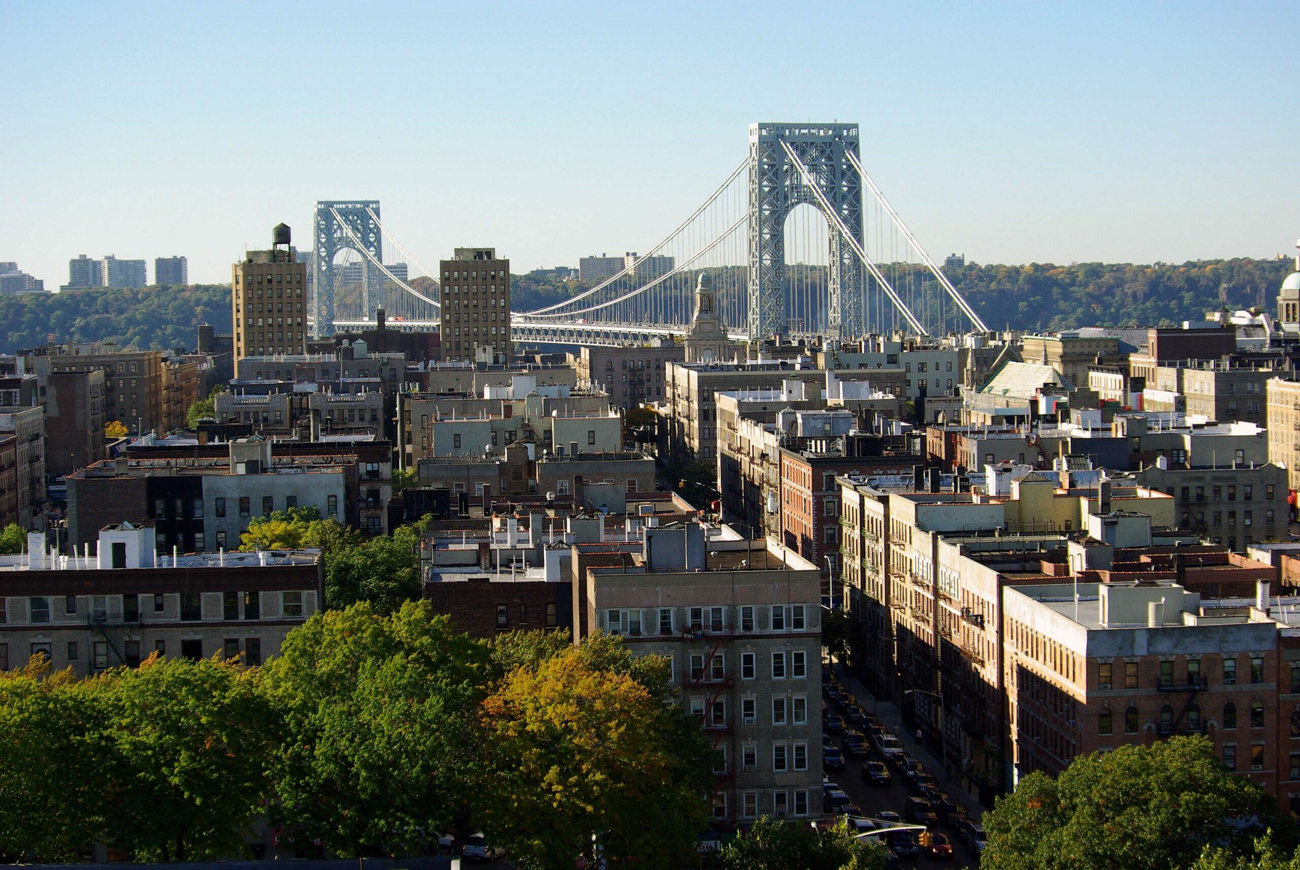 An aerial view of Washington Heights of New York City with the Brooklyn Bridge in the background.