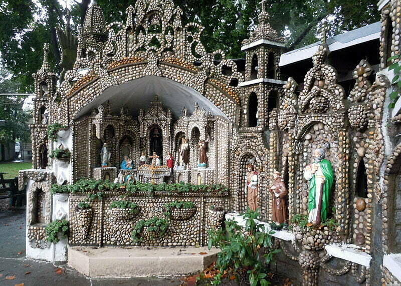 Grotto with several pebbles on the wall and with many statues of Christians.